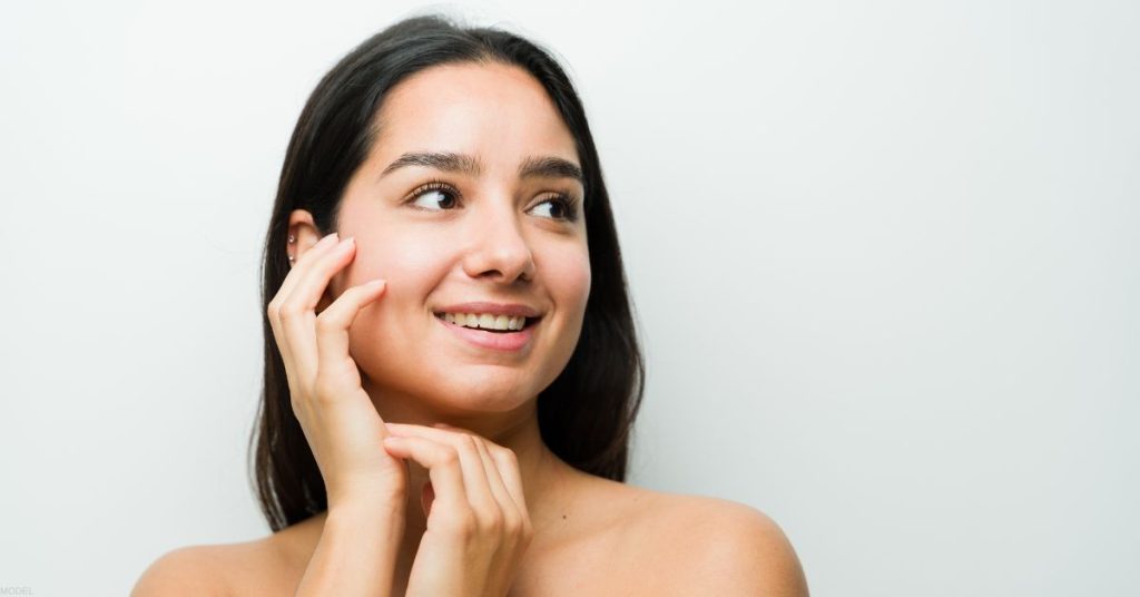 young woman (model) with clear skin smiles off into the distance