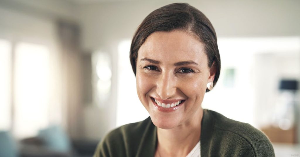 a female (model) in her early 40s smiles from her living room